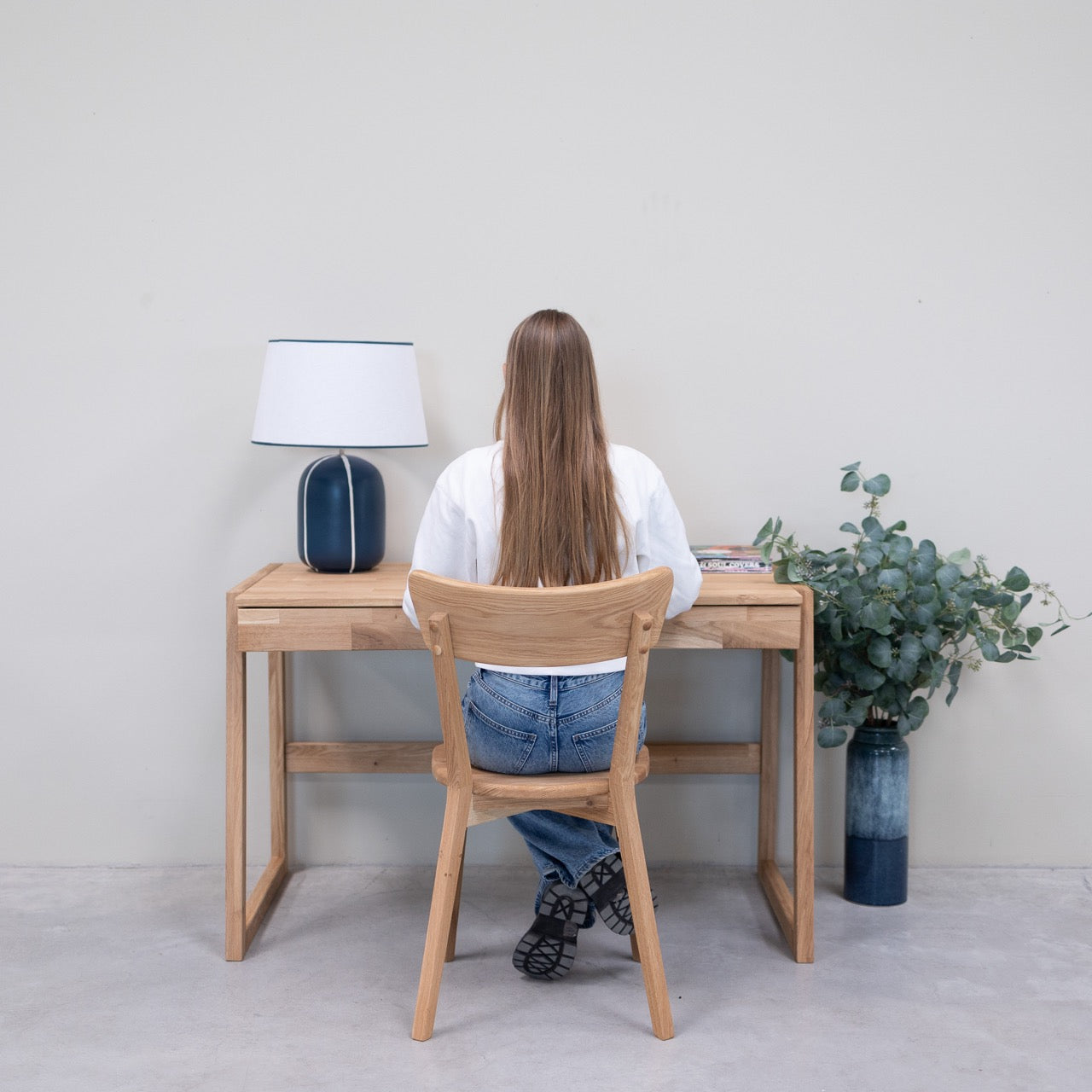 Persona sentada en una silla de escritorio de madera frente a un escritorio